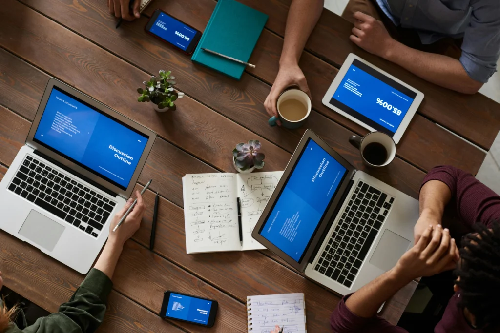A group of people collaborating at a table, each focused on their laptops,engaged in a work or discussion
